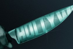 Hand holding a knife with the reflection of the Hollywood sign